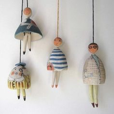 three wooden dolls hanging from strings on a wall