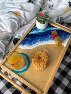 a tray with a doughnut, glass of orange juice and a potted plant on it