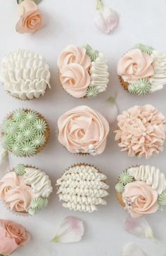 cupcakes with pink and green frosting are arranged on a white surface next to flowers