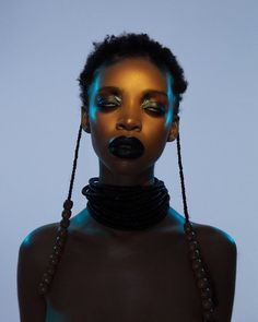 a woman with black makeup and beads on her neck