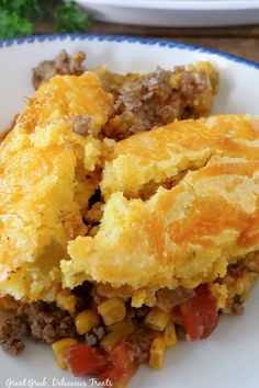 a white plate topped with an omelet and cornbread casserole covered in cheese