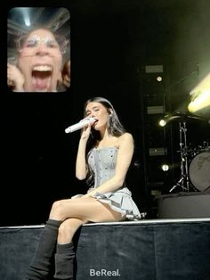 a woman sitting on top of a stage with a microphone in front of her face