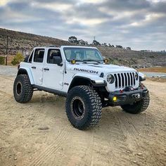 a white jeep parked on top of a dirt road