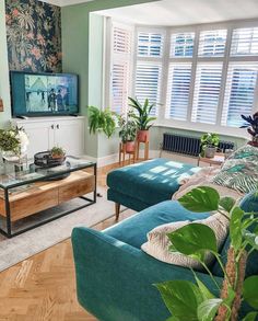 a living room with blue couches and green plants on the table in front of it