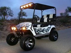 a white golf cart with black and white designs on it's front lights is driving down the road