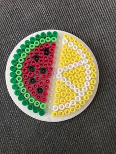 a white plate topped with lots of different colored bead designs on top of a gray surface