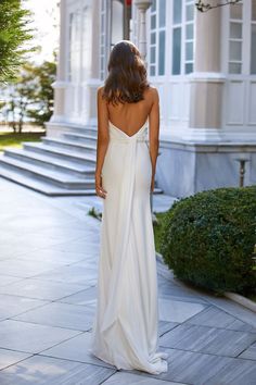 the back of a woman's dress as she walks down a sidewalk in front of a building