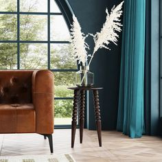 a brown leather chair sitting in front of a window next to a vase with white flowers