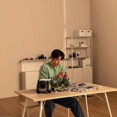 a young man sitting at a table working on a project with an old sewing machine