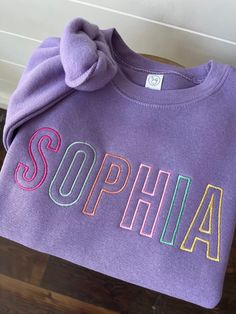 This cozy pullover sweatshirt is cotton/poly blend is embroidered with your little one's name across the front of the chest in the prettiest colors! Color shown is lavender which is not listed on the chart but is available in the drop down menu.  Please wash on cold and dry on low. If you are wanting a different design, more wording, or a different clothing style, please send me a message so we can discuss the details. Please leave the thread color you would like in the personalization box. Purple Long Sleeve Sweater With Letter Print, Long Sleeve Fleece Top With Letter Embroidery, Fleece Top With Letter Embroidery And Long Sleeves, Fleece Crew Neck Tops For School, Purple Letter Print Sweater For Fall, Cute Multicolor Crew Neck Sweatshirt, Cute Cotton Sweatshirt With Embroidered Logo, Cute Cotton Sweatshirt With Embroidered Graphics, Multicolor Fleece Crew Neck Sweatshirt