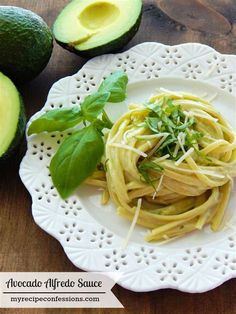 an avocado and pasta dish on a white plate next to sliced avocados