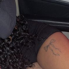 a woman laying on the floor next to a car seat with a tattoo on her arm