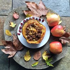 a white plate topped with food on top of a table next to apples and leaves