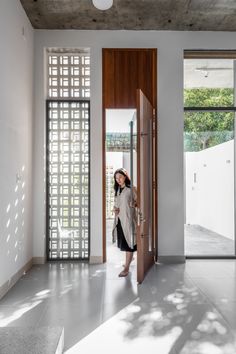 a woman standing in front of a doorway with her hand on the door handle and looking into the room