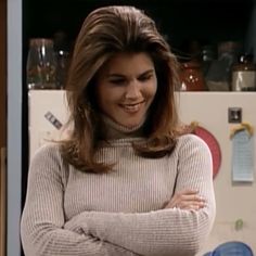 a woman standing in front of a refrigerator with her arms crossed