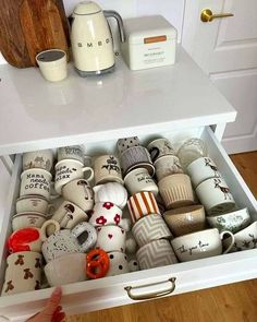 a drawer is filled with coffee cups and mugs