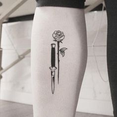 a black and white photo of a person with a rose on their leg holding a knife