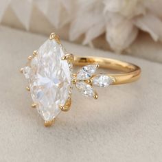 a gold ring with an oval cut diamond surrounded by small white diamonds on the side