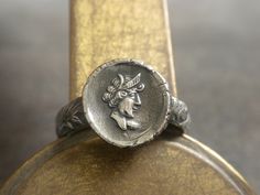 I handcrafted this wax seal jewelry Greek coin ring from precious metal silver clay and sterling silver .  The   impression was made by pressing a vintage intaglio into the metal clay.  The metal clay is then fired in my studio kiln, which burns off all the impurities and turns the clay to fine silver.  I then oxidized, tumbled and polished it to define the image.  The ring shank is sterling silver with a gorgeous floral pattern that I have soldered to the  disc. It is marked on the back with my makers mark and .999FS the fine silver mark. It depicts a Greek Goddess, although I can't be certain of which one.   Ready for Adventure. Thanks for looking at my shop: serrelynda.etsy.com Outlander Ring, Thistle Jewellery, Greek Mythology Jewelry, Seal Jewelry, Mythology Jewelry, Thistle Ring, Wax Seal Jewelry, Statement Cuff Bracelet, Silver Clay