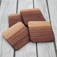 three square wooden coasters sitting on top of a white wood floor next to each other