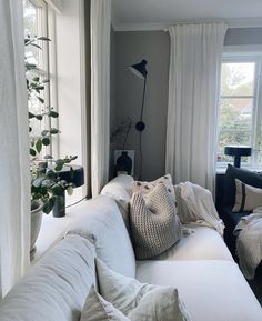 a living room with white couches and pillows on the floor, along with two windows