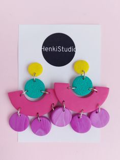 the pink and purple earrings are hanging from a card