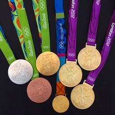 five olympic medals are displayed in front of each other on a black surface with colorful ribbons around them