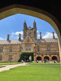 an archway leading to a large building with many people walking around the courtyard and onlookers