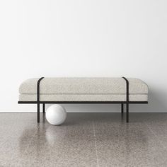 a white ball sitting on top of a black metal bench next to a white wall