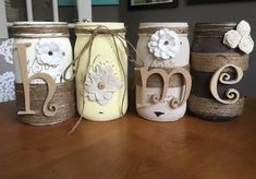 three mason jars are decorated with flowers and monogrammed letters on twine rope