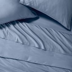 blue sheets and pillows are stacked on top of each other in this bedding set