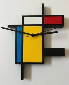 a clock made out of different colored blocks on a white wall with black hands and feet