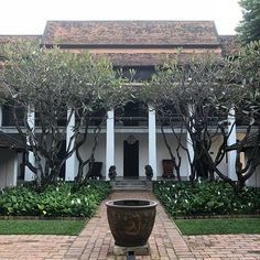 a large pot sitting on top of a brick walkway in front of a white building