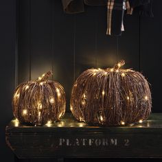 two pumpkins with fairy lights sitting on a table