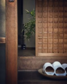 two pairs of white slippers sitting on top of a wooden tray in front of a door