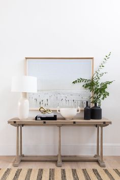 a wooden table topped with bowls and vases next to a wall mounted art piece