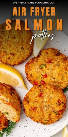 fried salmon patties on a white plate with lemon wedges and rosemary garnish