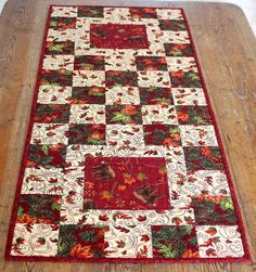 a red and white quilted table runner on top of a wooden floor next to a window