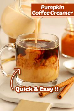 pumpkin coffee creamer is being poured into a glass mug with cinnamon sticks on the side