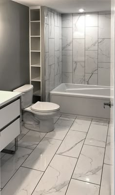 a bathroom with white marble tile floors and walls, along with a toilet and bathtub