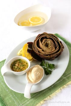 a white plate topped with food on top of a green table cloth next to two bowls