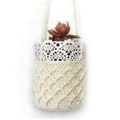 a white crochet bag with a succulent in it