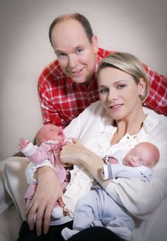 a man and woman holding a baby in their arms while posing for a photo together