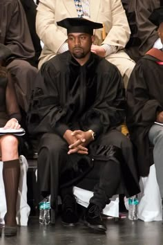 a man wearing a black hat sitting in front of other people at a graduation ceremony