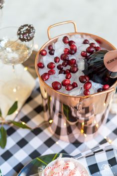 an ice bucket filled with cranberries on top of a checkered table cloth