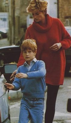 a woman walking next to a little boy near a car and another person holding something in his hand