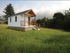 a small white house sitting on top of a lush green field