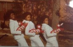 three people in white suits holding red and white items with the letters dg on them