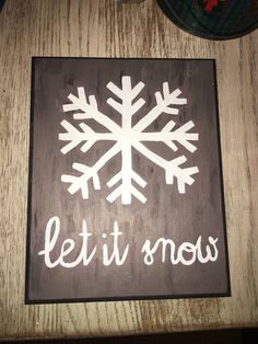 a sign that says let it snow on the side of a wooden table next to a plate