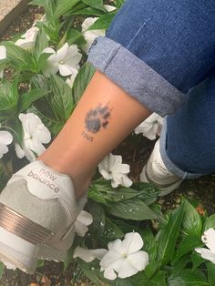 a person with a dog paw tattoo on their left leg and foot in front of white flowers